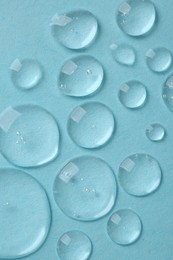 Photo of Drops of cosmetic serum on light blue background, top view