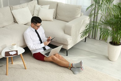 Businessman in shirt and underwear having video call on laptop at home