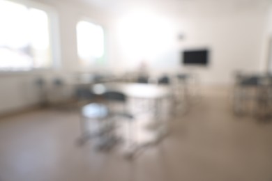 Photo of Blurred viewempty school classroom with desks, windows and chairs