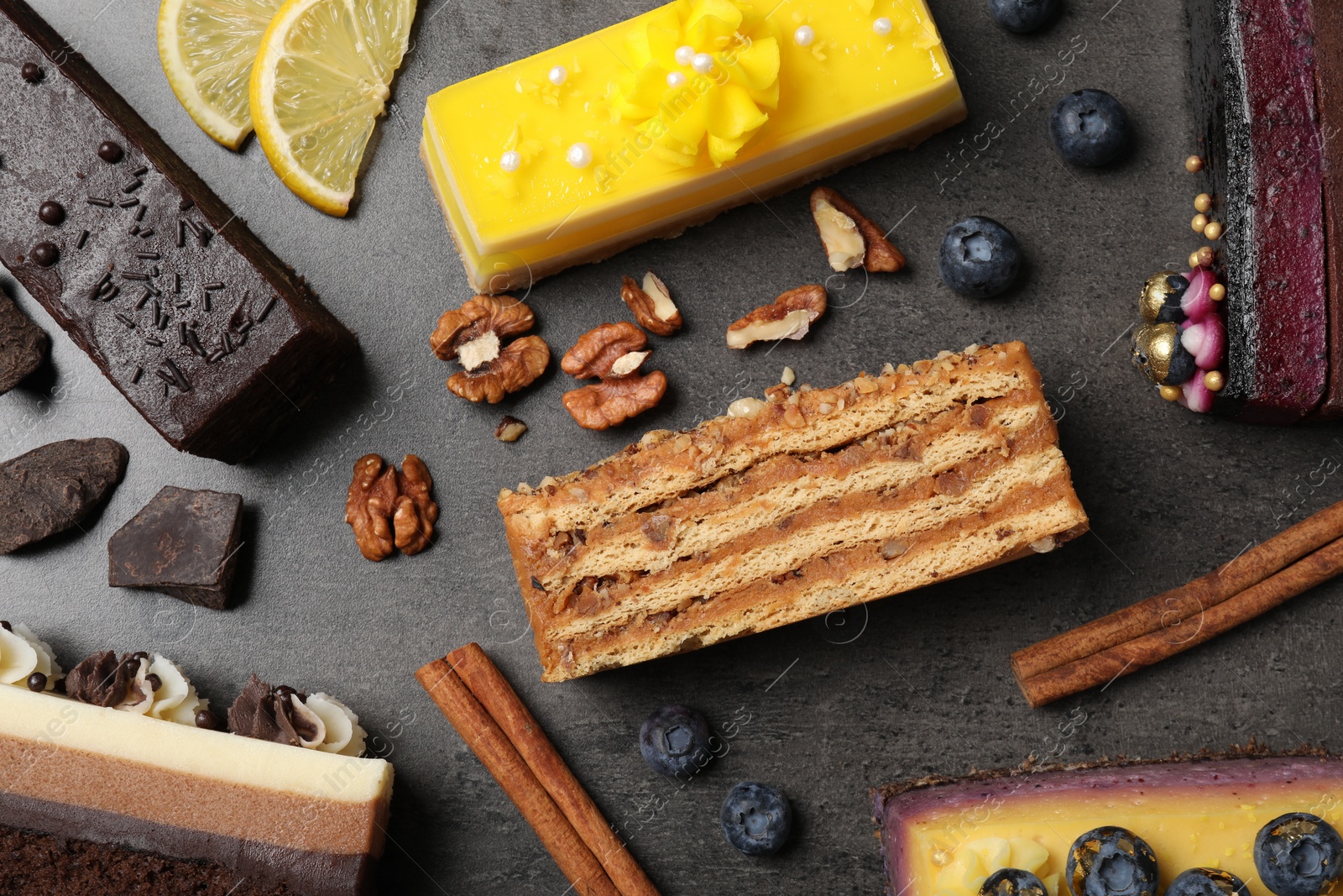 Photo of Different delicious cakes and ingredients on grey table, flat lay