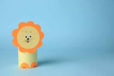Photo of Toy lion made from toilet paper hub on light blue background, space for text. Children's handmade ideas