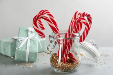 Photo of Christmas candy canes and confetti on light grey table