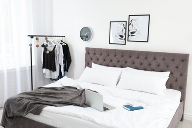 Stylish room interior with laptop and books on bed