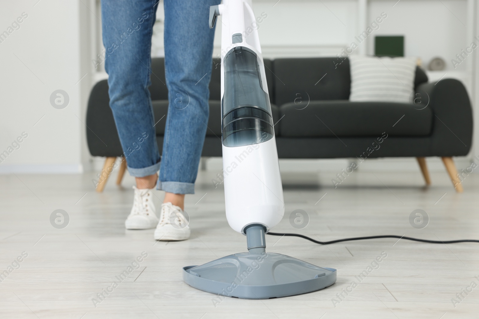 Photo of Woman cleaning floor with steam mop at home, closeup