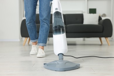 Woman cleaning floor with steam mop at home, closeup