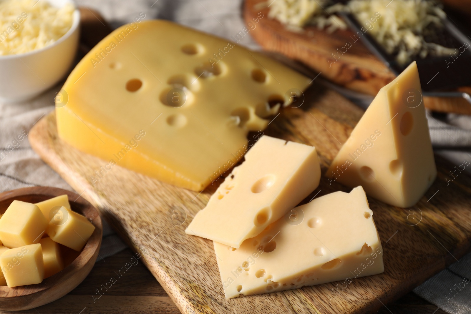 Photo of Grated and cut cheese on wooden table