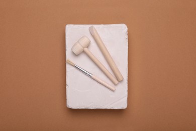 Photo of Educational toy for motor skills development. Excavation kit (plaster, digging tools and brush) on brown background, top view