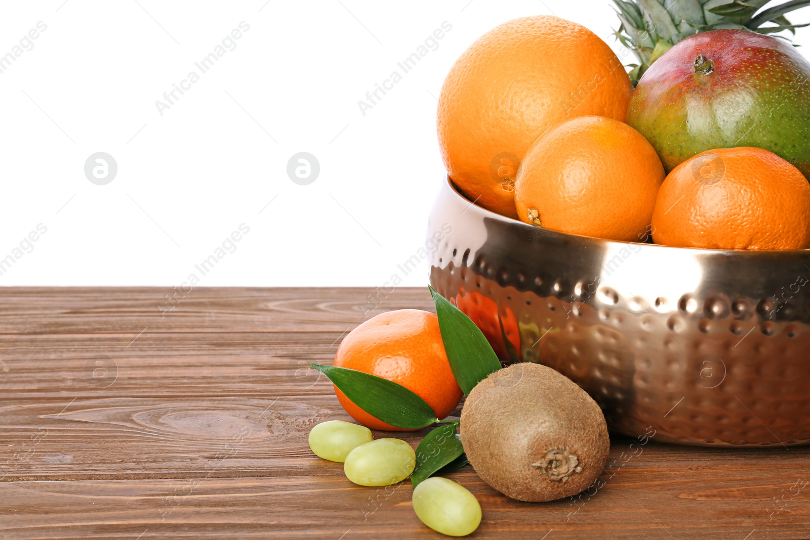 Photo of Metal bowl with fresh tropical fruits on wooden table