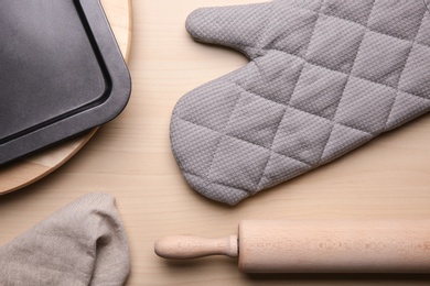 Photo of Flat lay composition with oven glove and kitchenware on wooden table