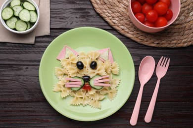 Photo of Creative serving for kids. Plate with cute cat made of tasty pasta, vegetables and sausage on wooden table, flat lay
