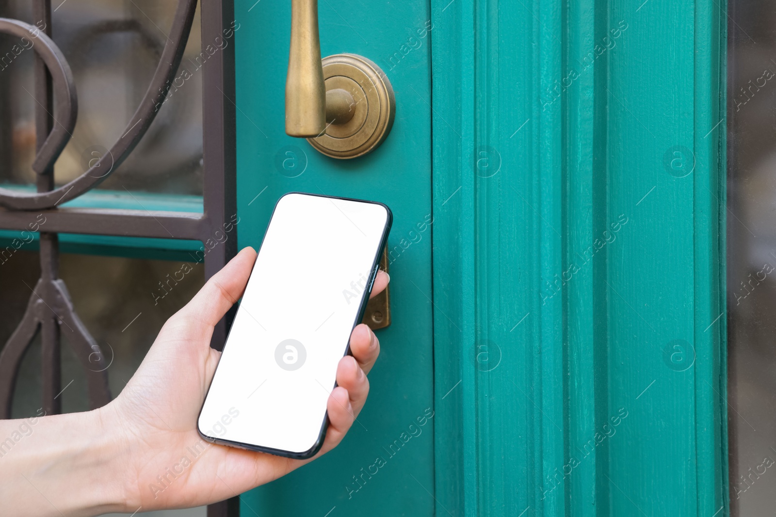 Photo of Woman opening door with smartphone outdoors, closeup