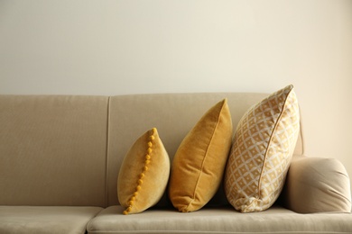 Image of Three pillows on sofa near wall in room. Interior design