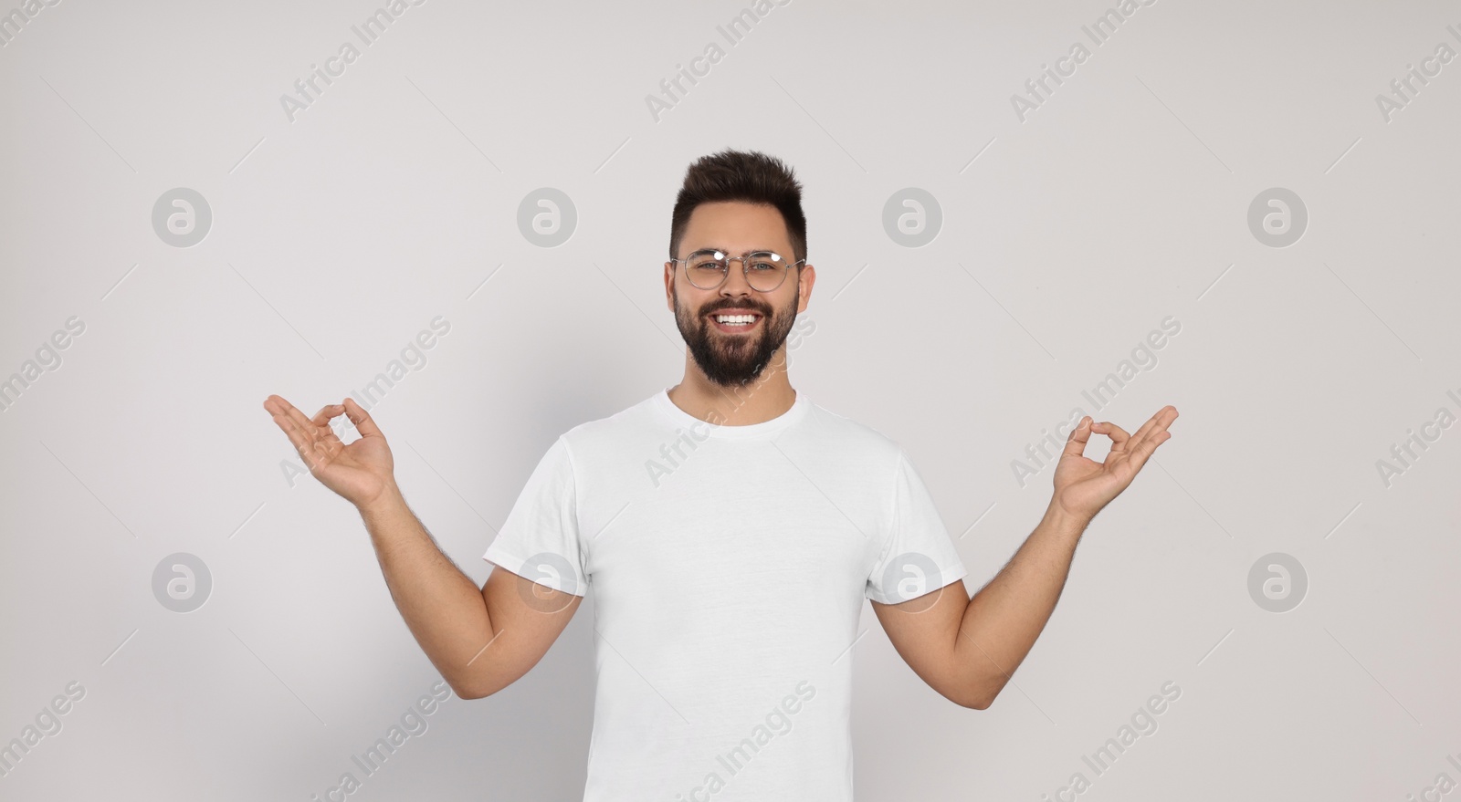 Photo of Young man meditating on white background. Zen concept