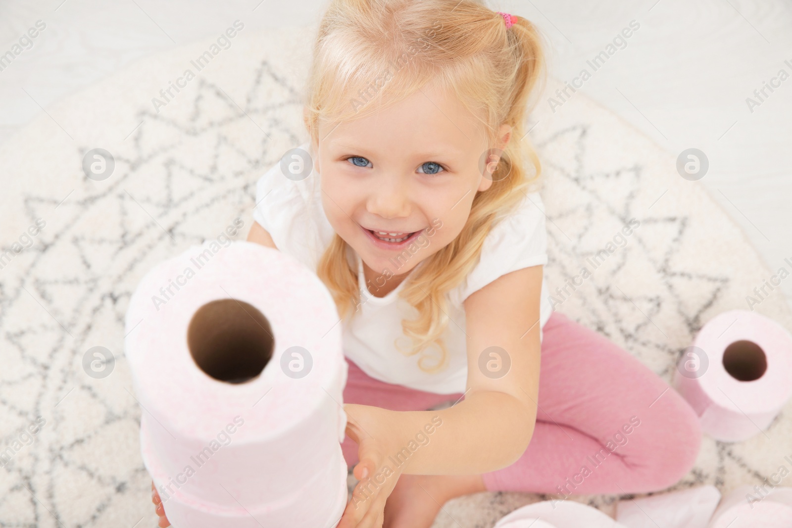 Photo of Cute little girl playing with toilet paper in bathroom