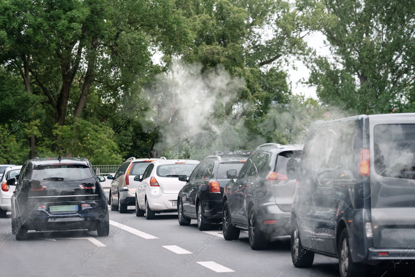 Image of Environmental pollution. Air contaminated with fumes in city. Cars surrounded by exhaust on road