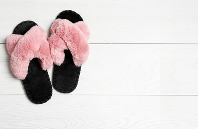 Photo of Pair of soft slippers on white wooden background, flat lay. Space for text