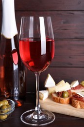 Delicious rose wine and snacks on wooden table