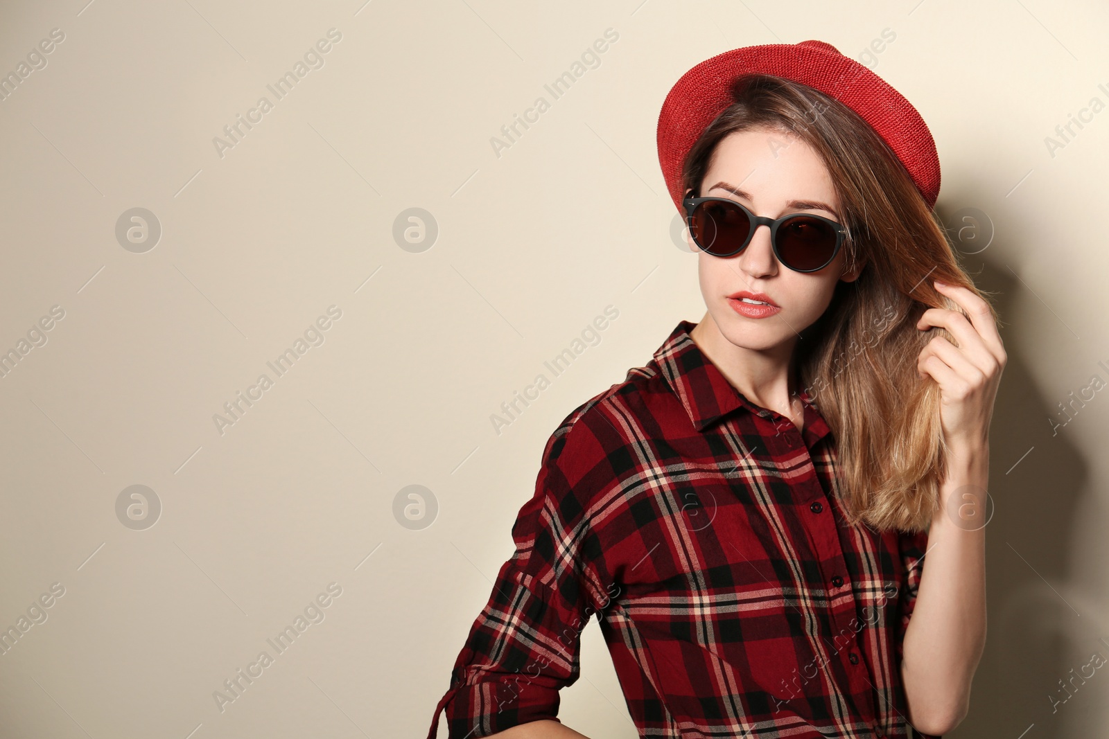 Photo of Young woman wearing stylish sunglasses on beige background. Space for text