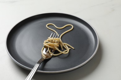 Photo of Heart made of tasty spaghetti and fork on white marble table