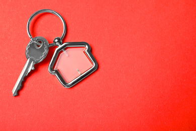 Photo of Key with trinket in shape of house on red background, top view and space for text. Real estate agent services