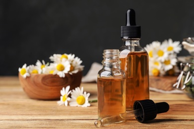 Photo of Composition with bottles of chamomile essential oil on table. Space for text