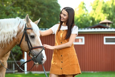 Palomino horse in bridle and young woman outdoors