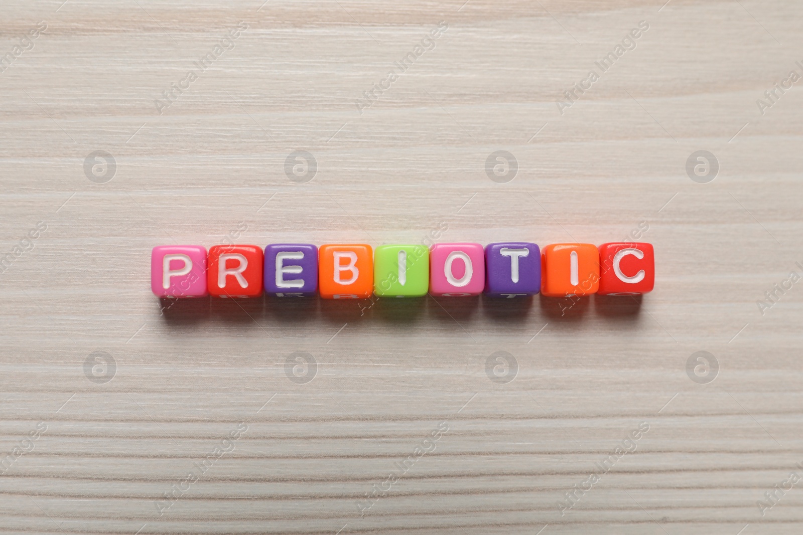 Photo of Word Prebiotic made of cubes with letters on wooden table, top view