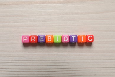 Photo of Word Prebiotic made of cubes with letters on wooden table, top view