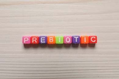 Word Prebiotic made of cubes with letters on wooden table, top view