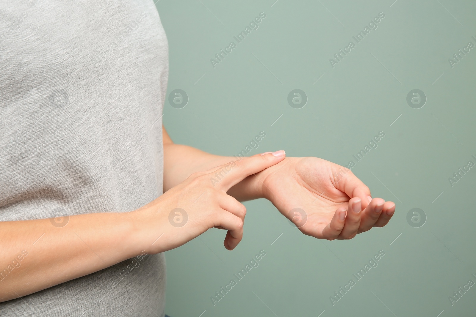 Photo of Young woman checking pulse on color background