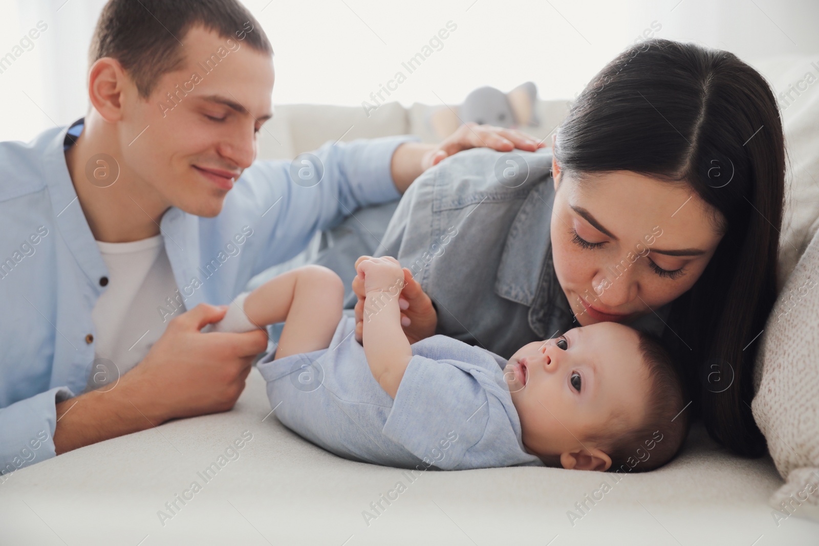 Photo of Happy family with cute baby on sofa at home