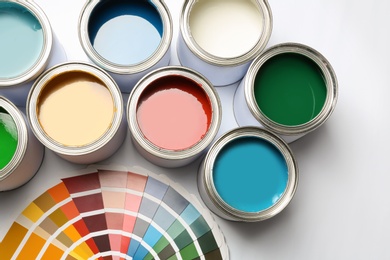 Paint cans and color palette on white background, top view