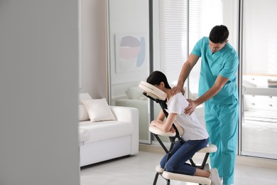 Woman receiving massage in modern chair indoors