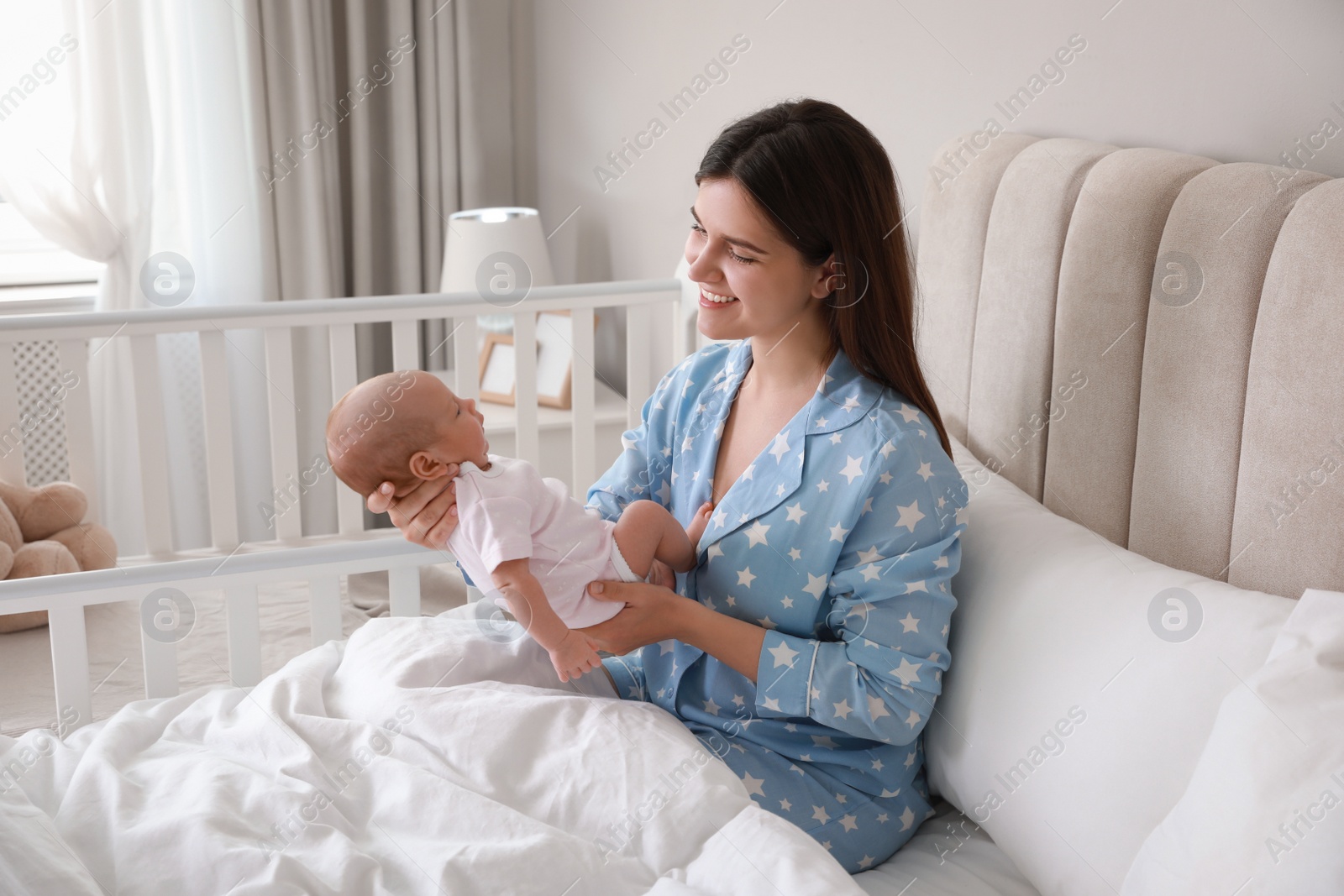 Photo of Happy young mother with her cute newborn baby in bed at home