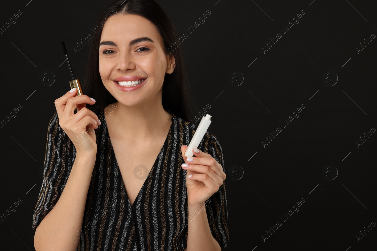 Photo of Beautiful young woman with mascara on black background, space for text