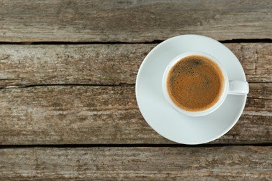 Photo of Cup of tasty coffee on wooden table, top view. Space for text