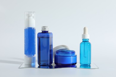 Different containers with cosmetic products on light background