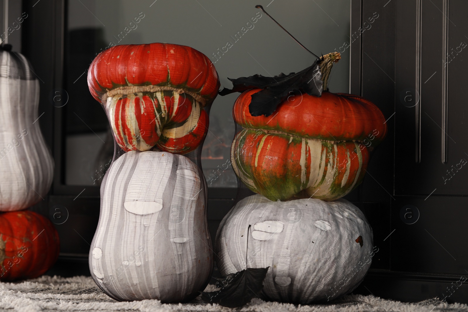 Photo of Colorful pumpkins on rug near fireplace. Halloween decorations