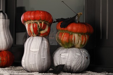 Photo of Colorful pumpkins on rug near fireplace. Halloween decorations