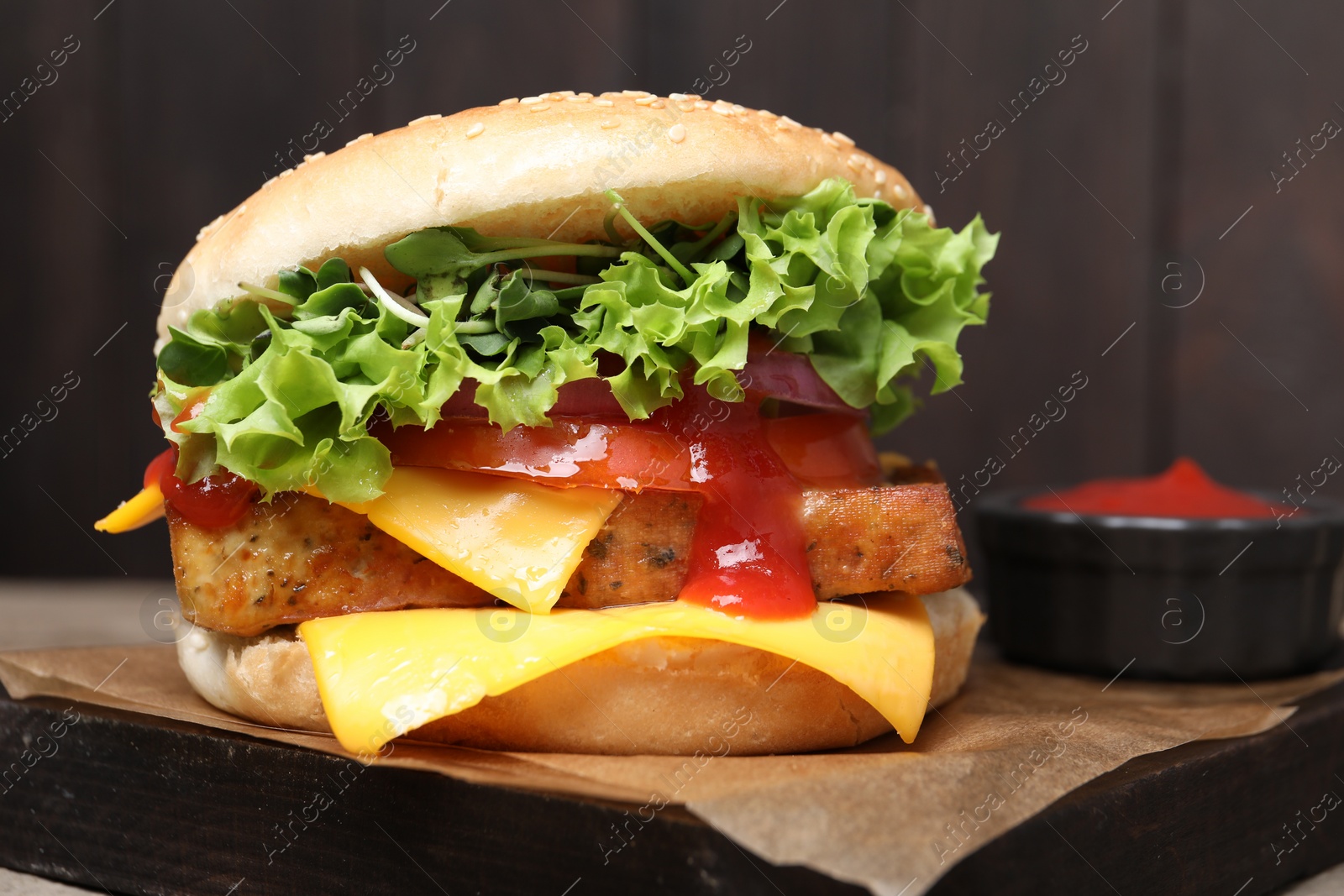 Photo of Delicious tofu burger served with sauce on board, closeup