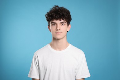 Photo of Portrait of cute teenage boy on light blue background