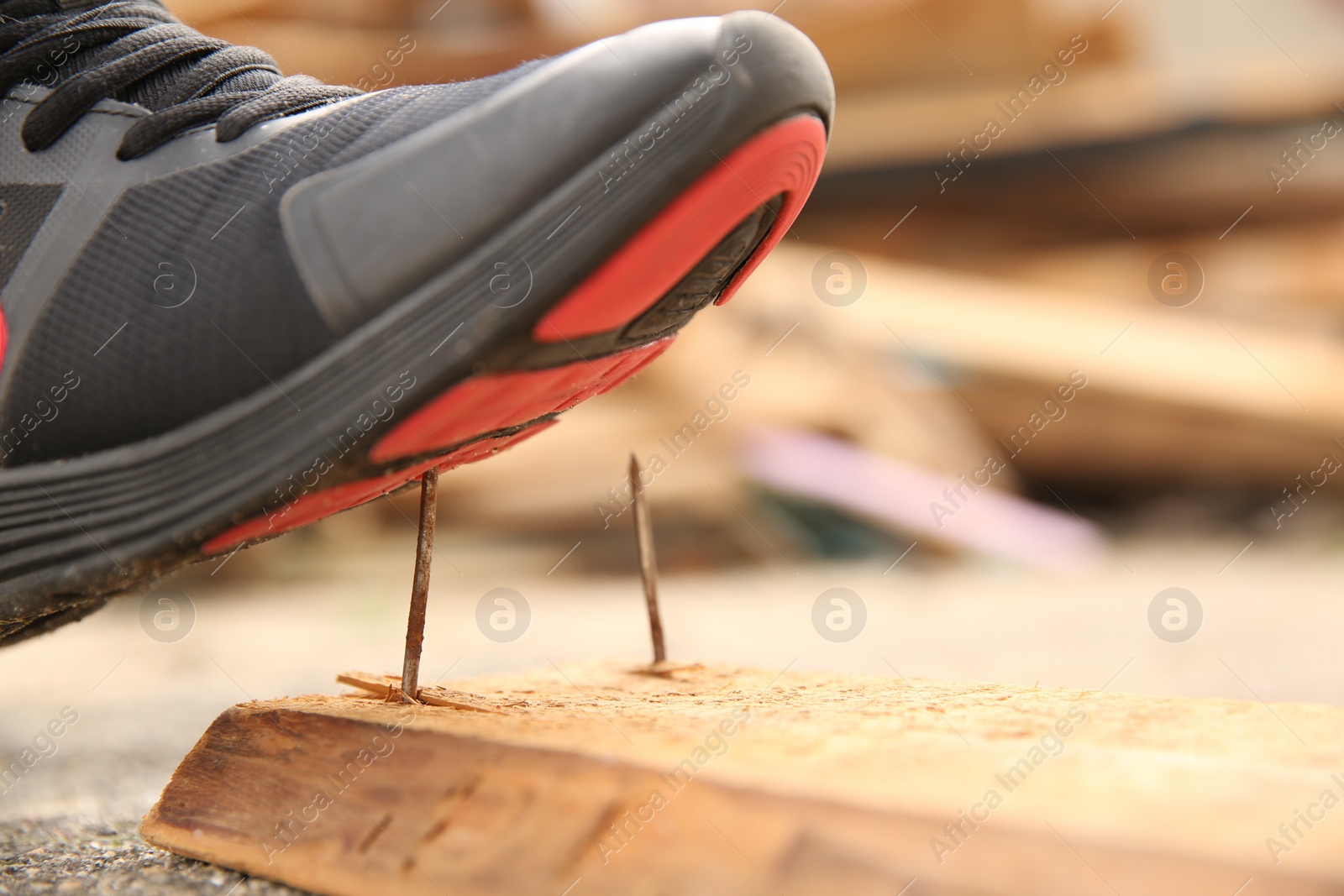 Photo of Careless worker stepping on nail in wooden plank outdoors, closeup. Space for text