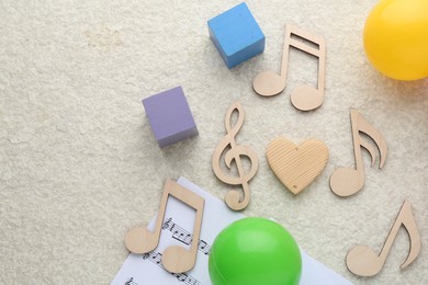 Wooden notes, music sheet and toys on beige textured background, flat lay with space for text. Baby song concept