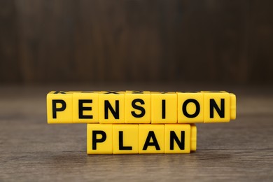 Photo of Words Pension Plan made of yellow cubes on wooden table, closeup