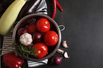 Cooking delicious ratatouille. Fresh ripe vegetables and colander on dark grey table, flat lay. Space for text