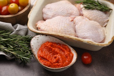 Marinade, raw chicken and rosemary on brown table, closeup