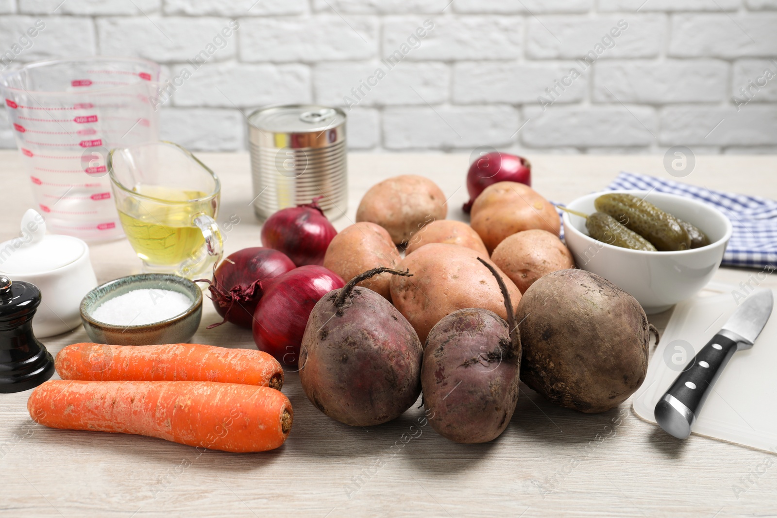 Photo of Many fresh vegetables and other ingredients on white wooden table. Cooking vinaigrette salad