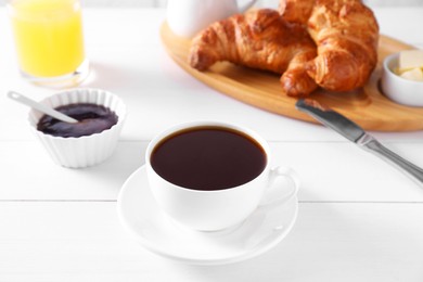 Photo of Fresh croissants, jam and coffee on white wooden table. Tasty breakfast