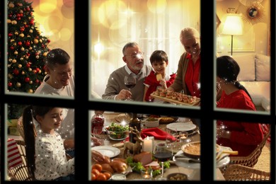 Happy family enjoying festive dinner at home, view through window. Christmas celebration