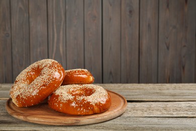 Delicious fresh bagels with sesame seeds on wooden table, space for text